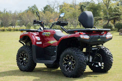 Red ATV parked on grass with trees in the background